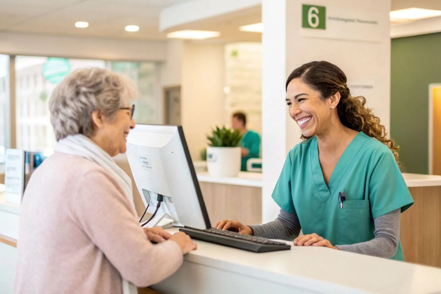 Profissional atendendo cliente em balcão de unidade de saúde, sorrindo e utilizando computador para cadastro, representando o atendimento humanizado na Unimed